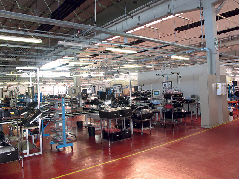 Nell’area di produzione quello che si effettua è un lavoro di assemblaggio e collaudo di parti che, pur provenendo da produttori di tutto il mondo, sono progettate in Casa, realizzate ad hoc. Tutti i componenti ottici, realizzati in Giappone, sono frutto della creatività di Giorgio Barazza. I chip DMD ovviamente vengono da Texas Instruments. In Italia vengono realizzati i circuiti stampati, le plastiche dei cabinet, come anche i cablaggi e le parti per l’imballaggio. In quest’area dello stabilimento lavorano una quindicina di persone, con un ritmo produttivo che può arrivare alle 40 unità giornaliere (foto in alto a sinistra). 